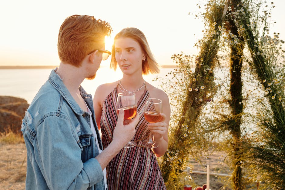 A couple enjoying wine during a romantic sunset outdoors by the water