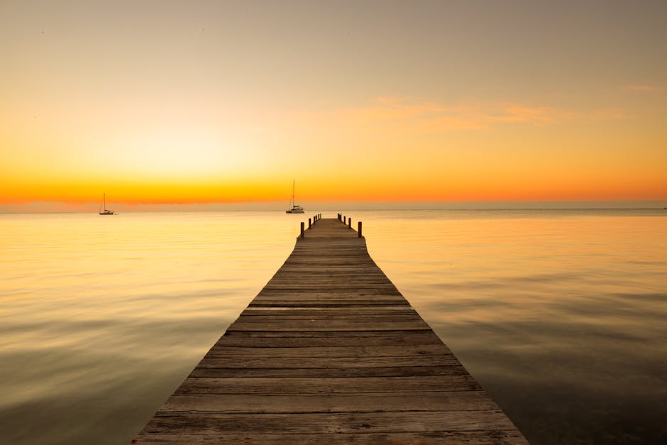 Wooden pier extends into tranquil sea at sunset in Belize, creating a warm, peaceful scene